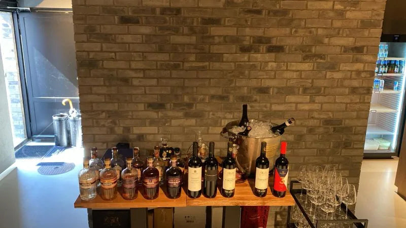 Bottles and glasses on a wooden table in front of a brick wall with a window in the club